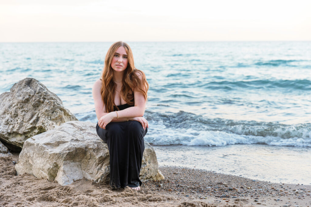 A beautiful girl sitting on a rock on Lake Michigan.