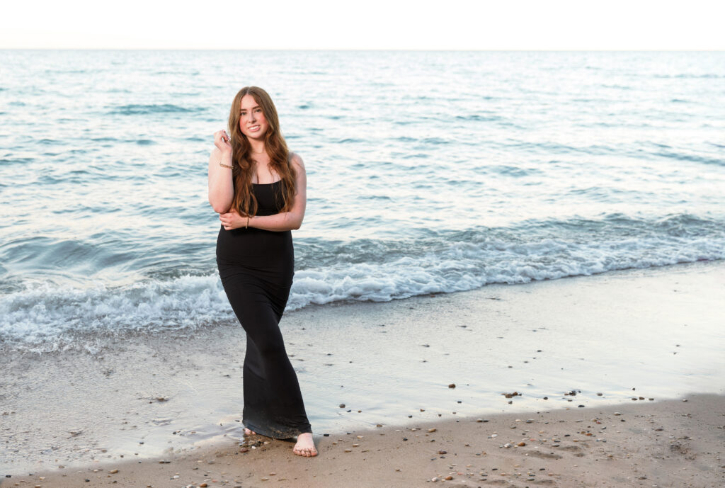 A girl standing at the shore of Lake Michigan for her senior photos.