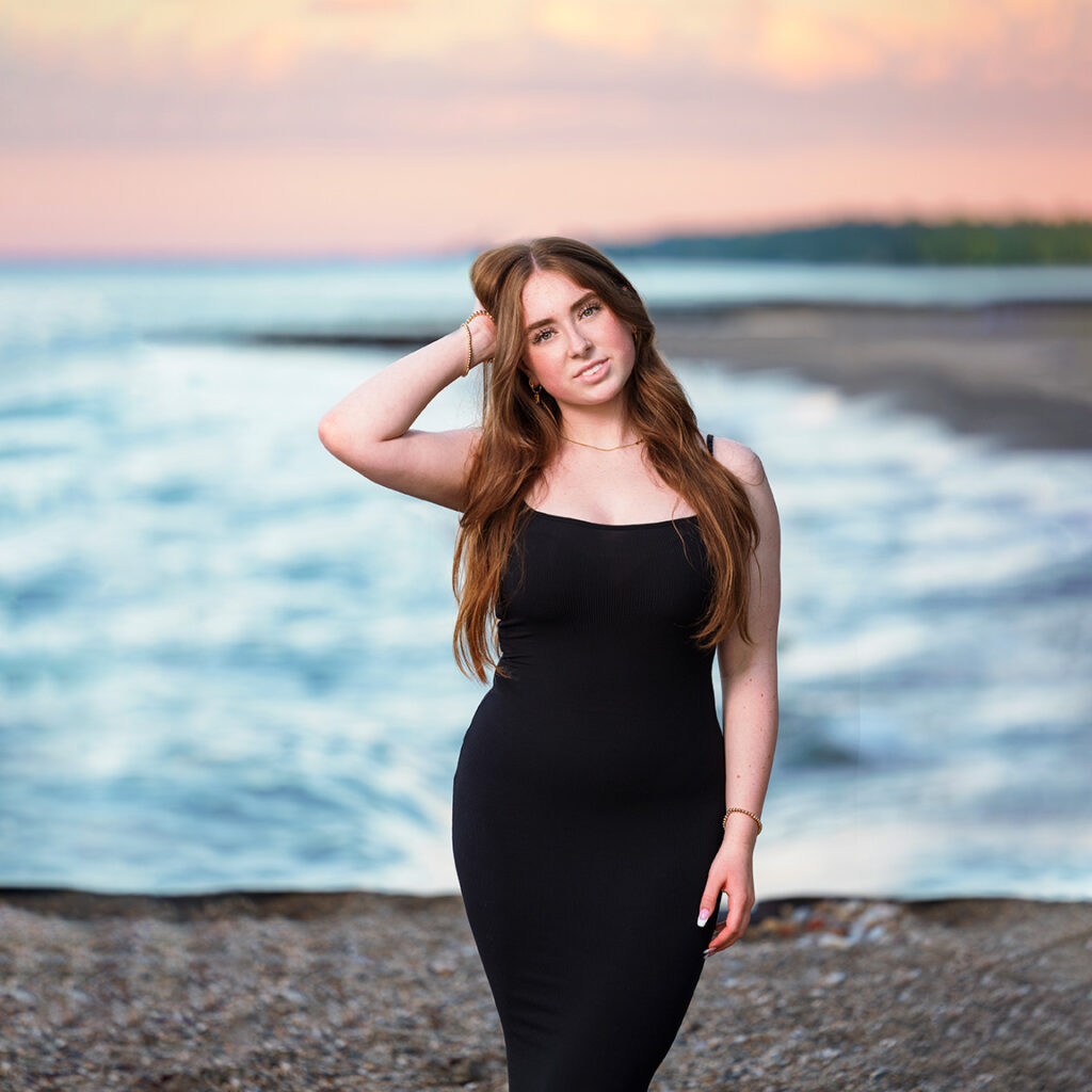 A girl in a black dress on Lake Michigan in Highland Park at sunset.